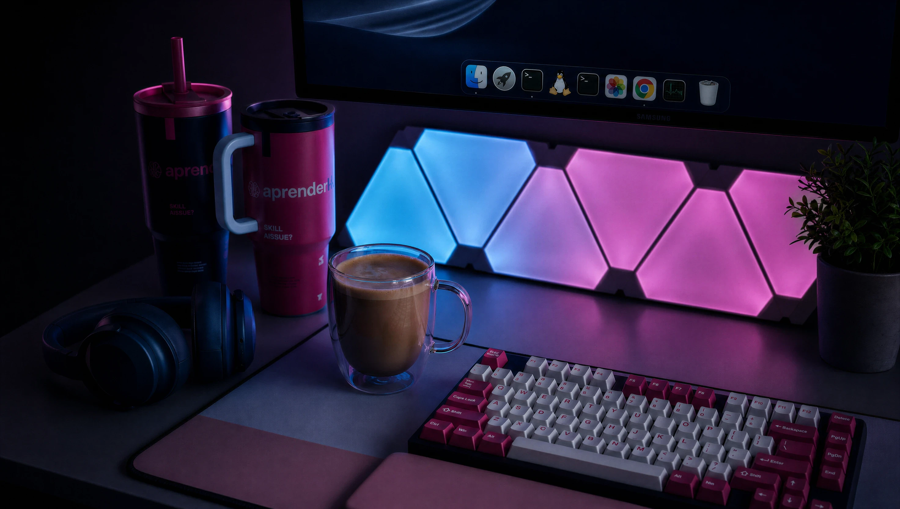 A desk at night lit by blue and magenta LED panels, with two aprenderIA tumblers, a cup of coffee, a mechanical keyboard and a pair of headphones